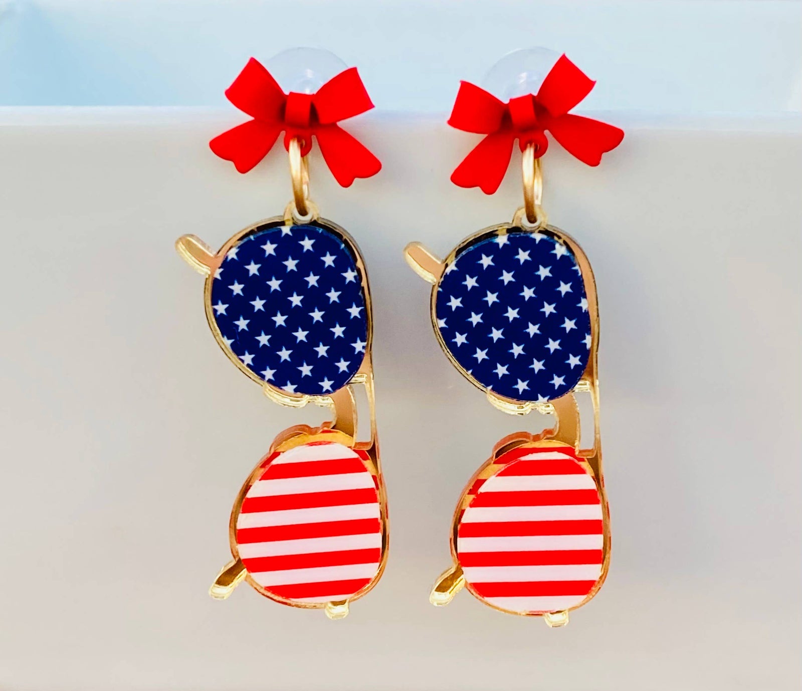 Sunglasses with American flag design and red bows on a light background