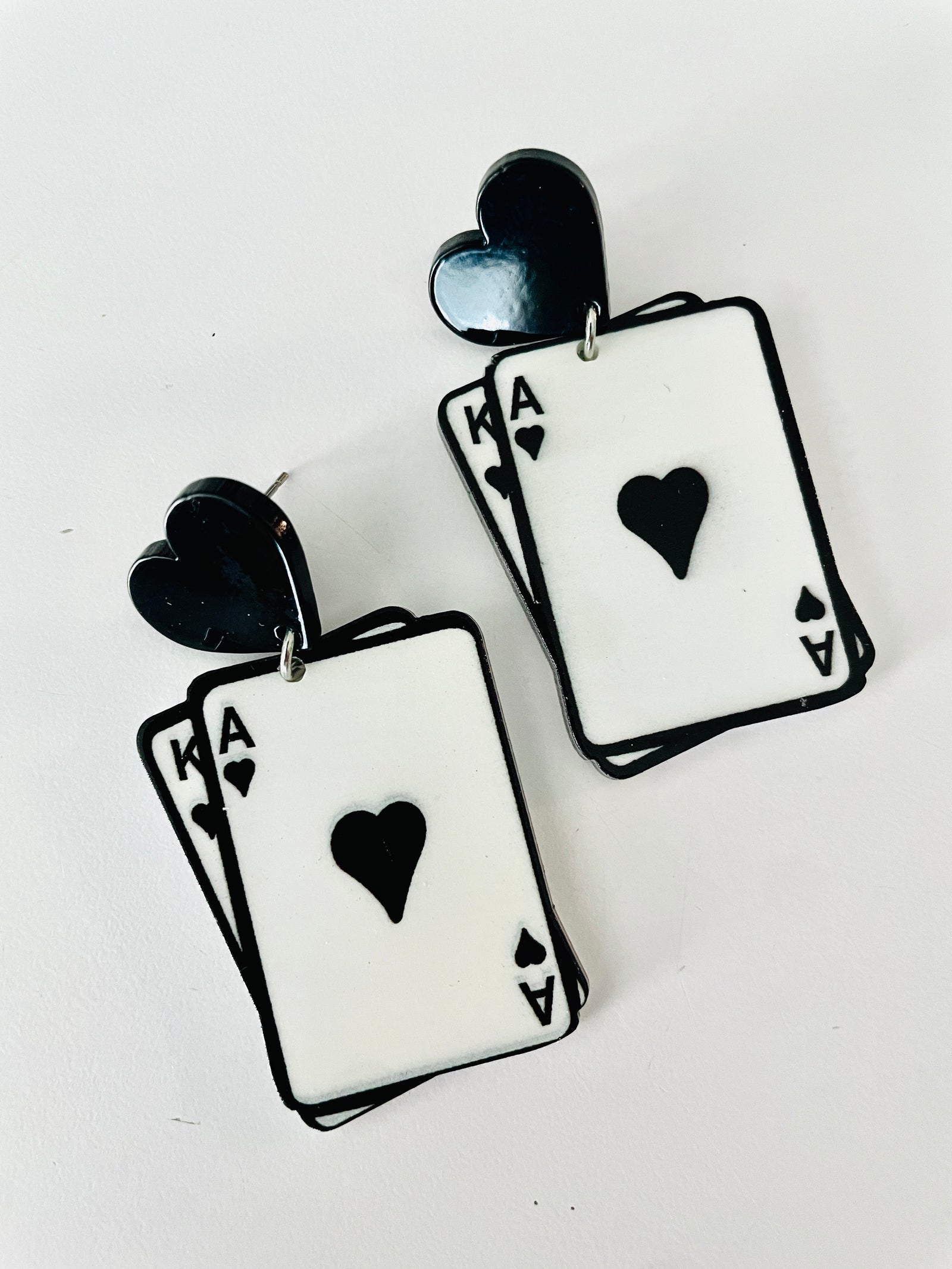 Christmas Cheer All Year pair of earrings shaped like overlapping Ace of Hearts playing cards, with black heart-shaped studs and black outlines on a white card face for Alice in Wonderland