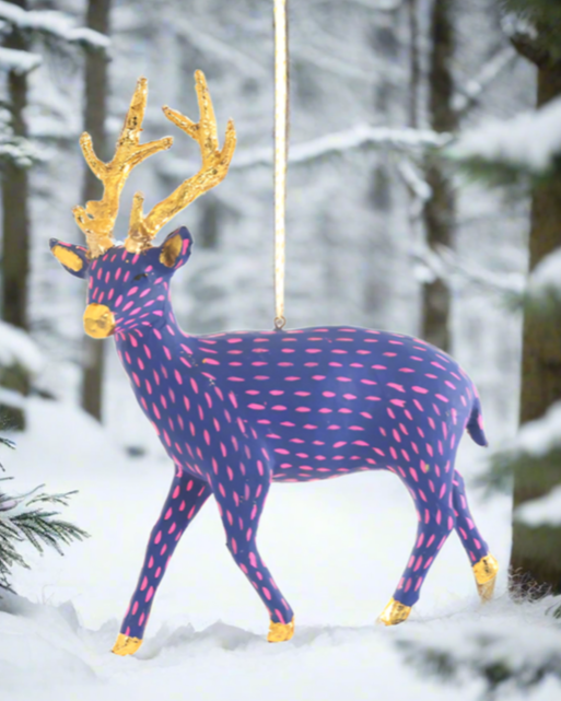 The Canton Christmas Shop Blue and Pink Paper Deer Ornament in the snowy woods at Christmas