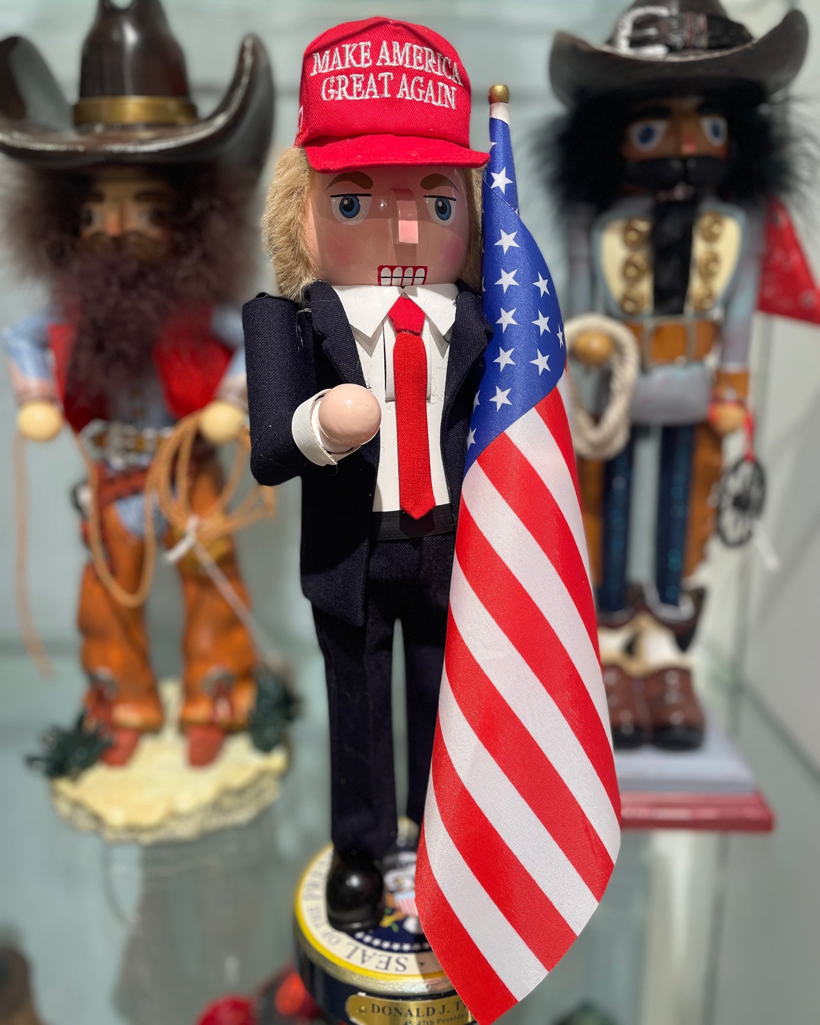 Christmas Cheer All Year Donald J. Trump Presidential Nutcracker Make America Great Again Red Baseball Cap Navy Suit American Flag on Pedestal by Kurt Adler G5013