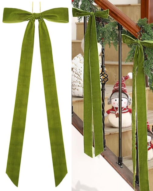 Green velvet ribbon bows on a staircase railing with Christmas decorations.