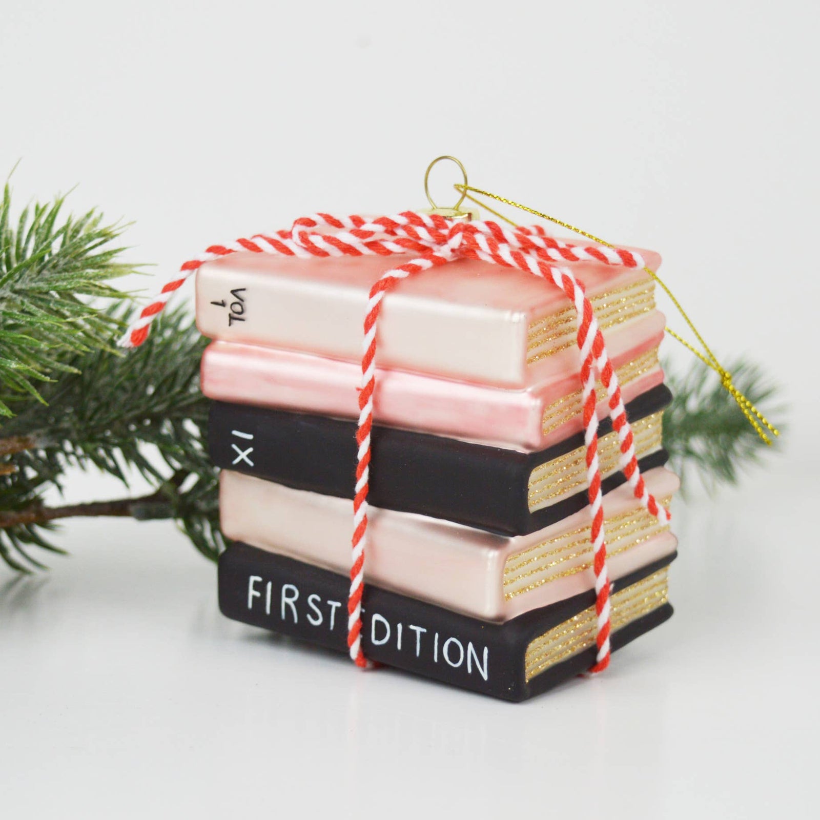 Christmas Cheer All Year Stack of decorative books ornament tied with red and white string on a white background