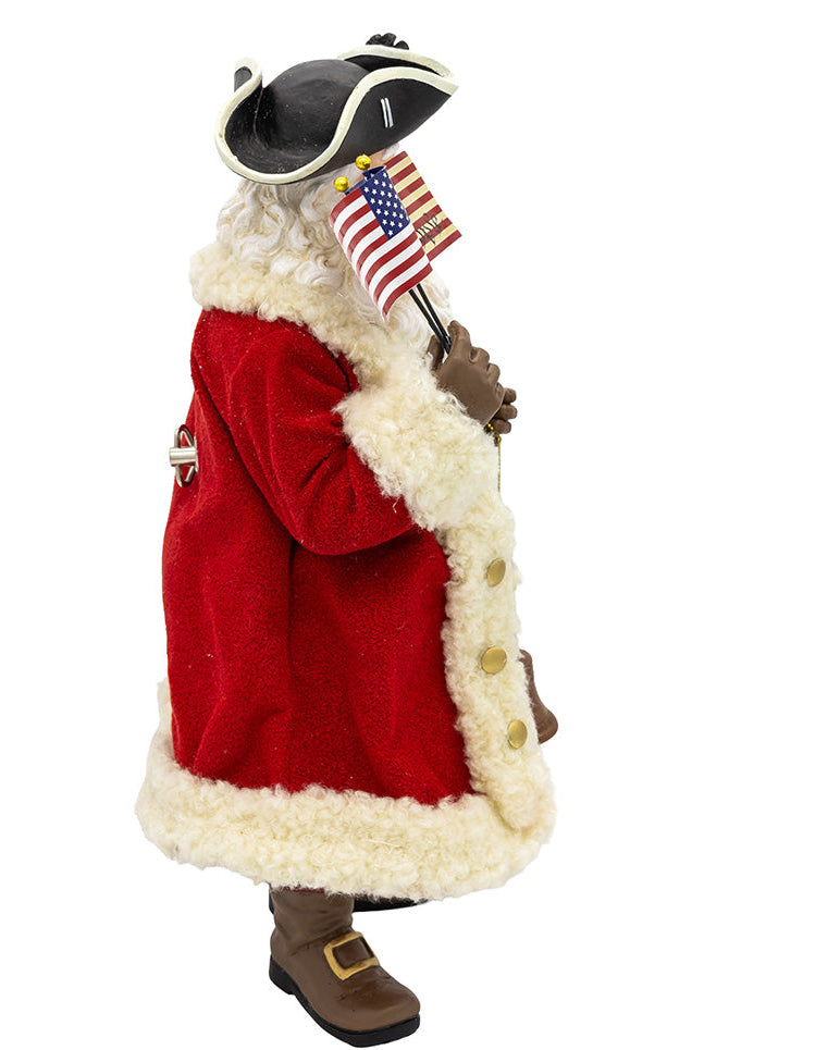 Christmas Cheer All Year FA0231 Santa 250th Figurine of a character in a red coat with white fur trim, holding an American flag on a white background