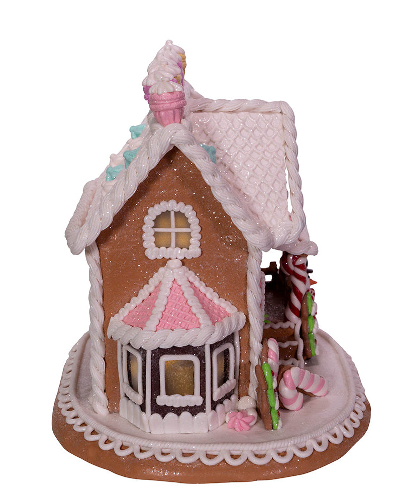 Decorative gingerbread house with pink and white details on a white background