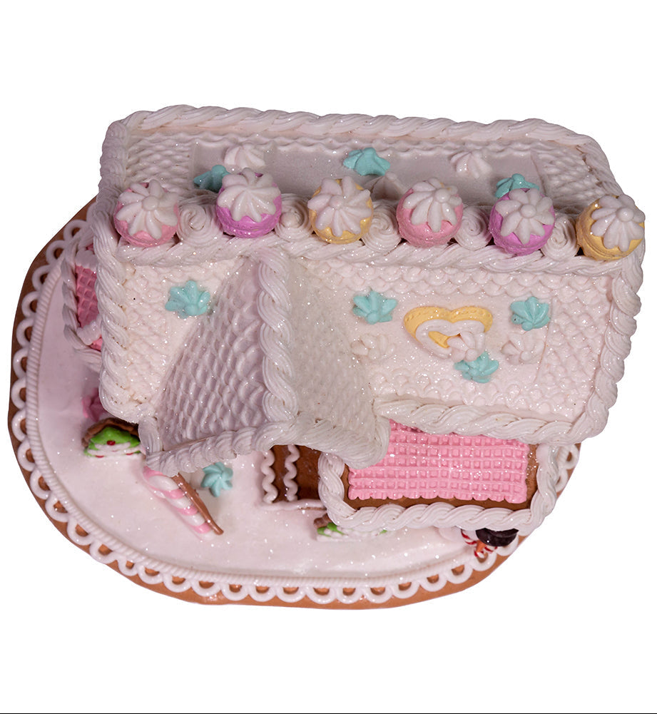 Decorative gingerbread house with pink interior and candy details on a white background