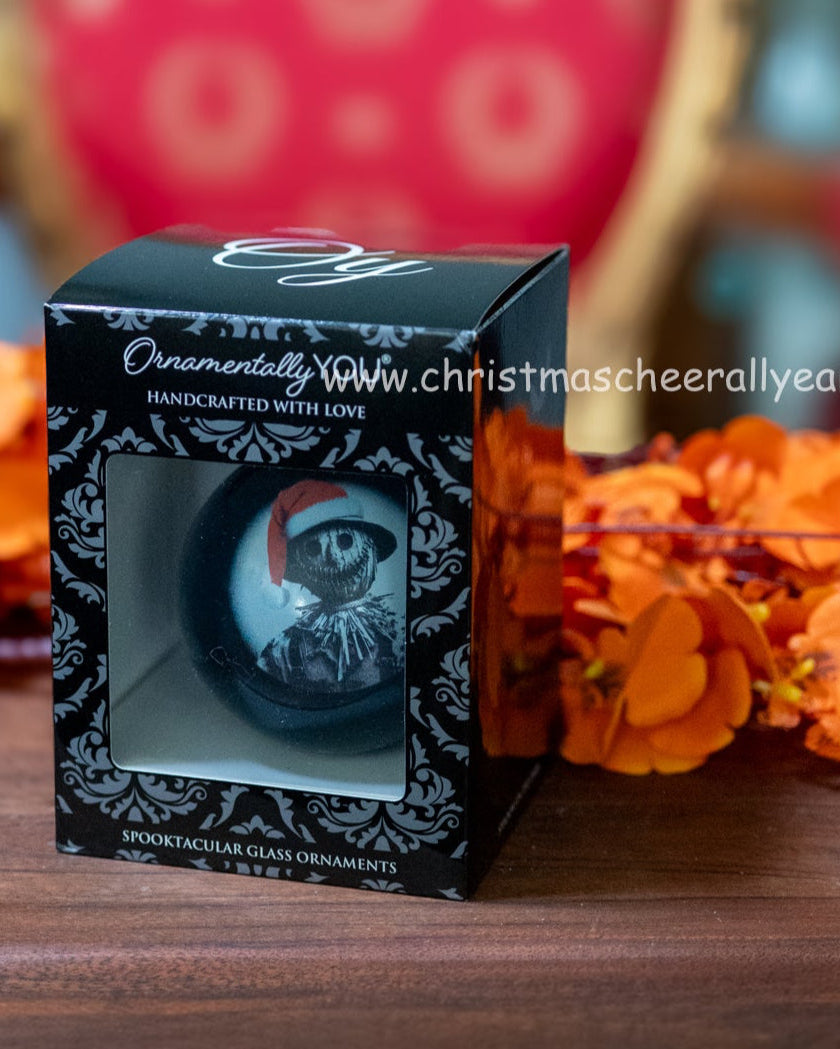 Decorative ornament packaging on a wooden surface with orange flowers and a red chair in the background.
