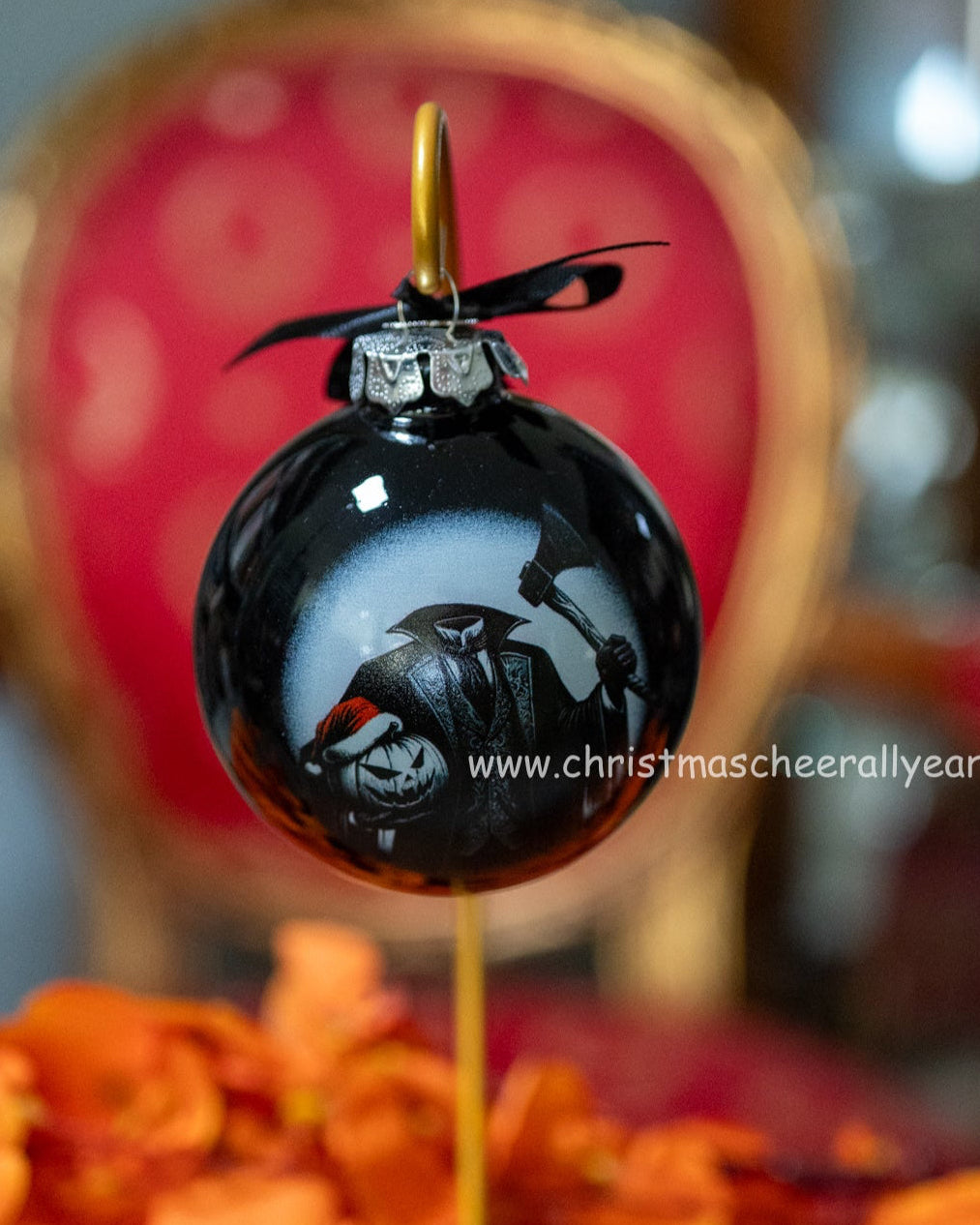 Decorative black headless horseman glass ball style ornament with a gold spike on a stand, surrounded by orange flowers.