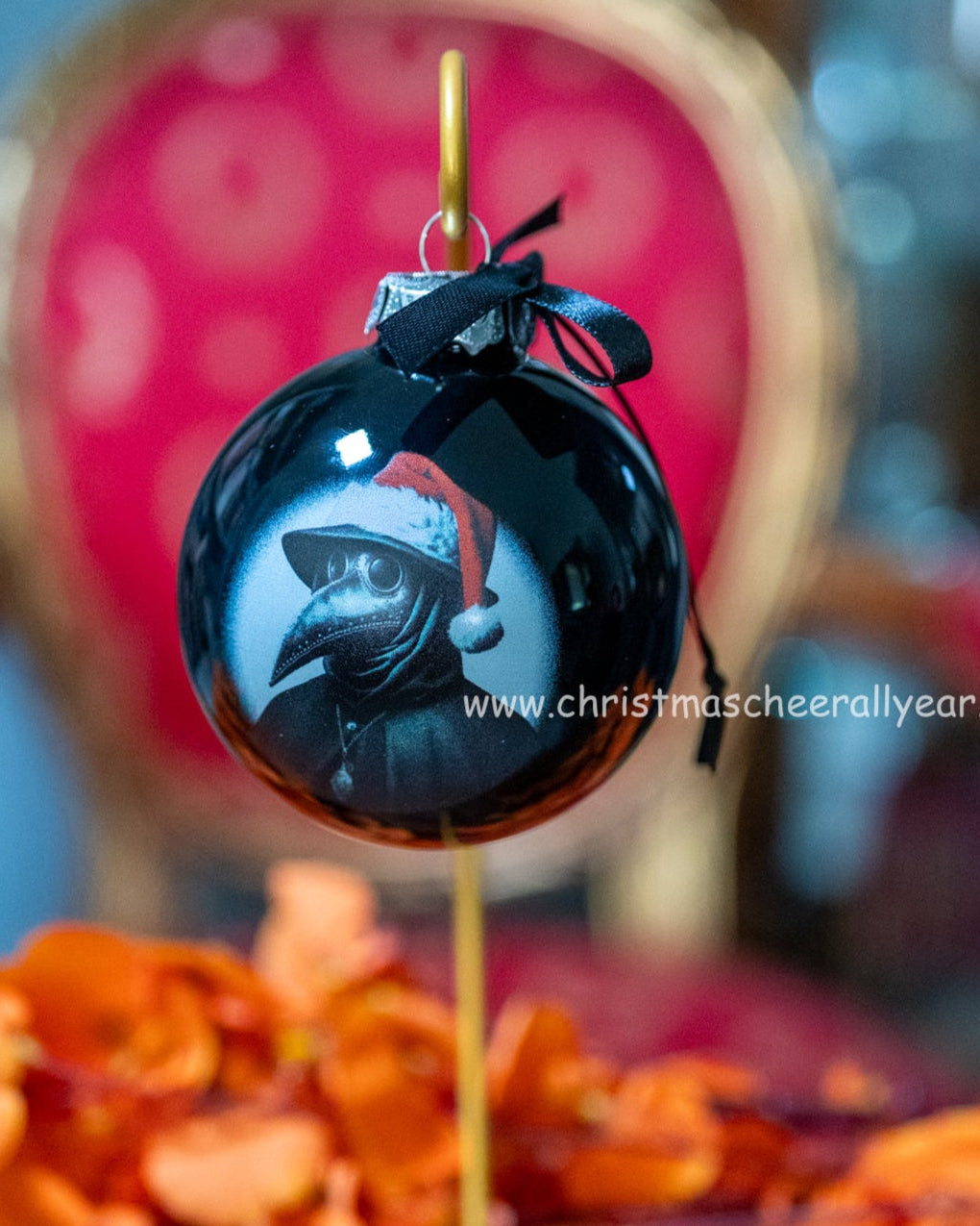 Black Christmas ornament with a plague doctor design and Santa hat, hanging on a blurred festive background.