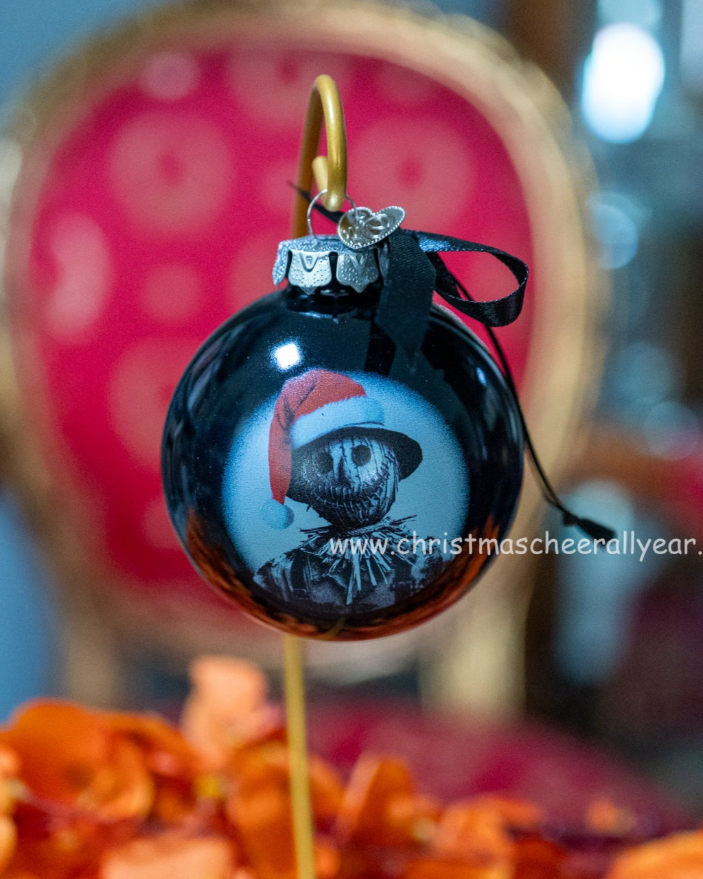 Black Christmas ornament with a scarecrow wearing a Santa hat on a blurred background