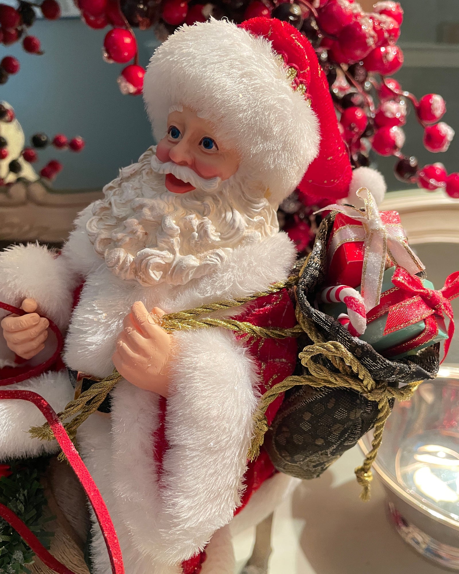 Christmas Cheer All Year 11.5" Fabriche Santa on Reindeer Figurine by Kurt Adler  wearing a red suit with white fur trim, a red hat, and a sack, sitting on a reindeer