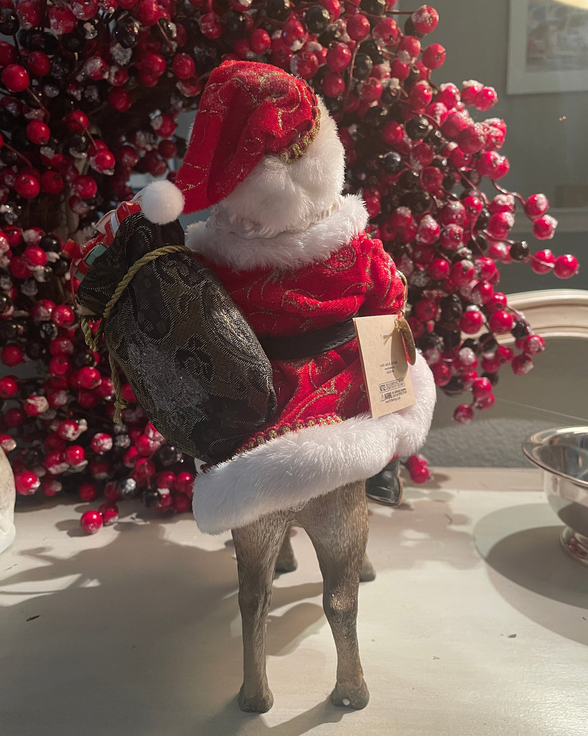 Christmas Cheer All Year 11.5" Fabriche Santa on Reindeer Figurine by Kurt Adler  wearing a red suit with white fur trim, a red hat, and a sack, sitting on a reindeer