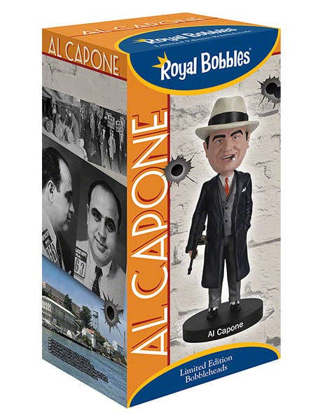 Al Capone Royal Bobbles collectible bobblehead in its original retail packaging. The box features a graphic of the Al Capone bobblehead wearing a black suit, gray vest, red tie, and a beige fedora hat, set against a white brick wall with bullet hole details.