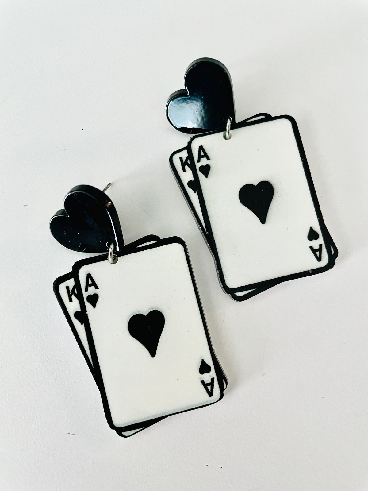 Christmas Cheer All Year pair of earrings shaped like overlapping Ace of Hearts playing cards, with black heart-shaped studs and black outlines on a white card face for Alice in Wonderland
