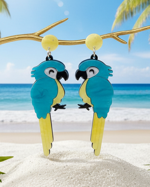 Christmas Cheer All Year Blue and yellow parrot acrylic earrings on a branch with a beach and palm trees in the background