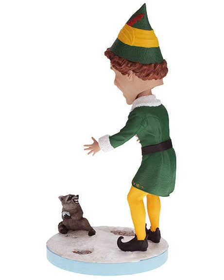Christmas Cheer All Year Scene from Elf the Movie Bobblehead figure of Buddy the Elf in green and yellow elf costume and hat with a raccoon on base that says "does someone need a hug?"