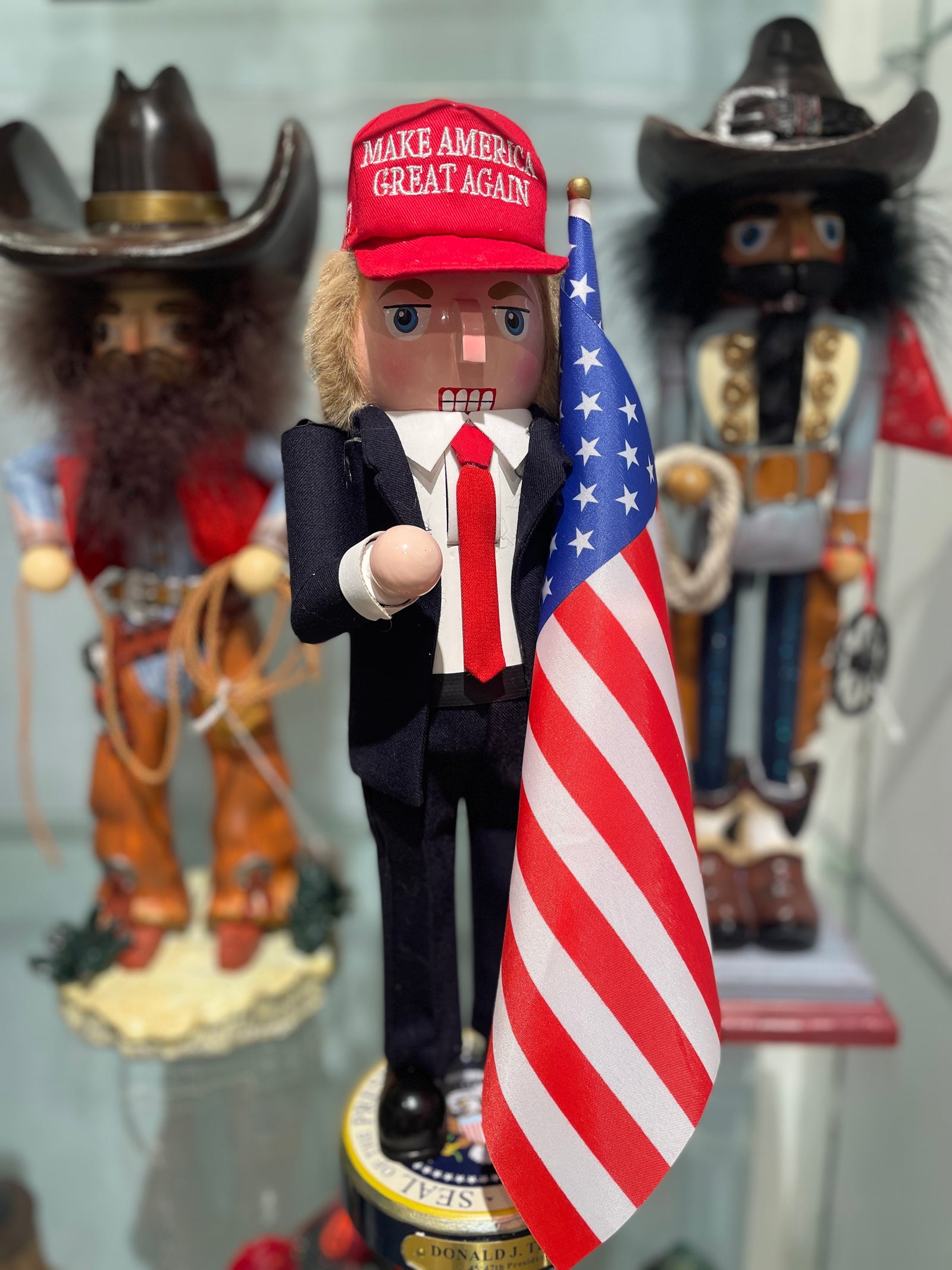 Christmas Cheer All Year Donald J. Trump Presidential Nutcracker Make America Great Again Red Baseball Cap Navy Suit American Flag on Pedestal by Kurt Adler G5013