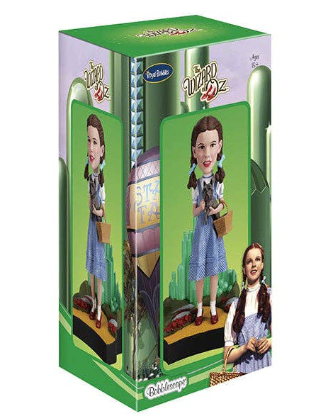 Christmas Cheer All Year  Dorothy from Wizard of Oz in a green and purple retail box, shown on a plain white background. The packaging features the Wizard of Oz title and a small Ozarks logo.