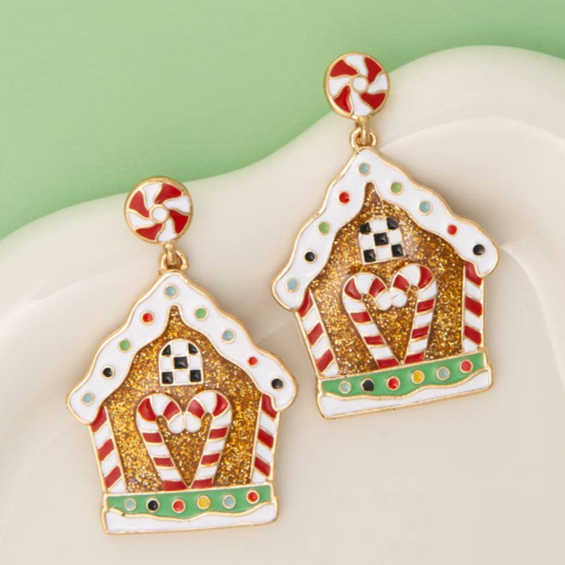 Gingerbread house enamel earrings with candy cane details on a white surface Christmas Cheer All Year