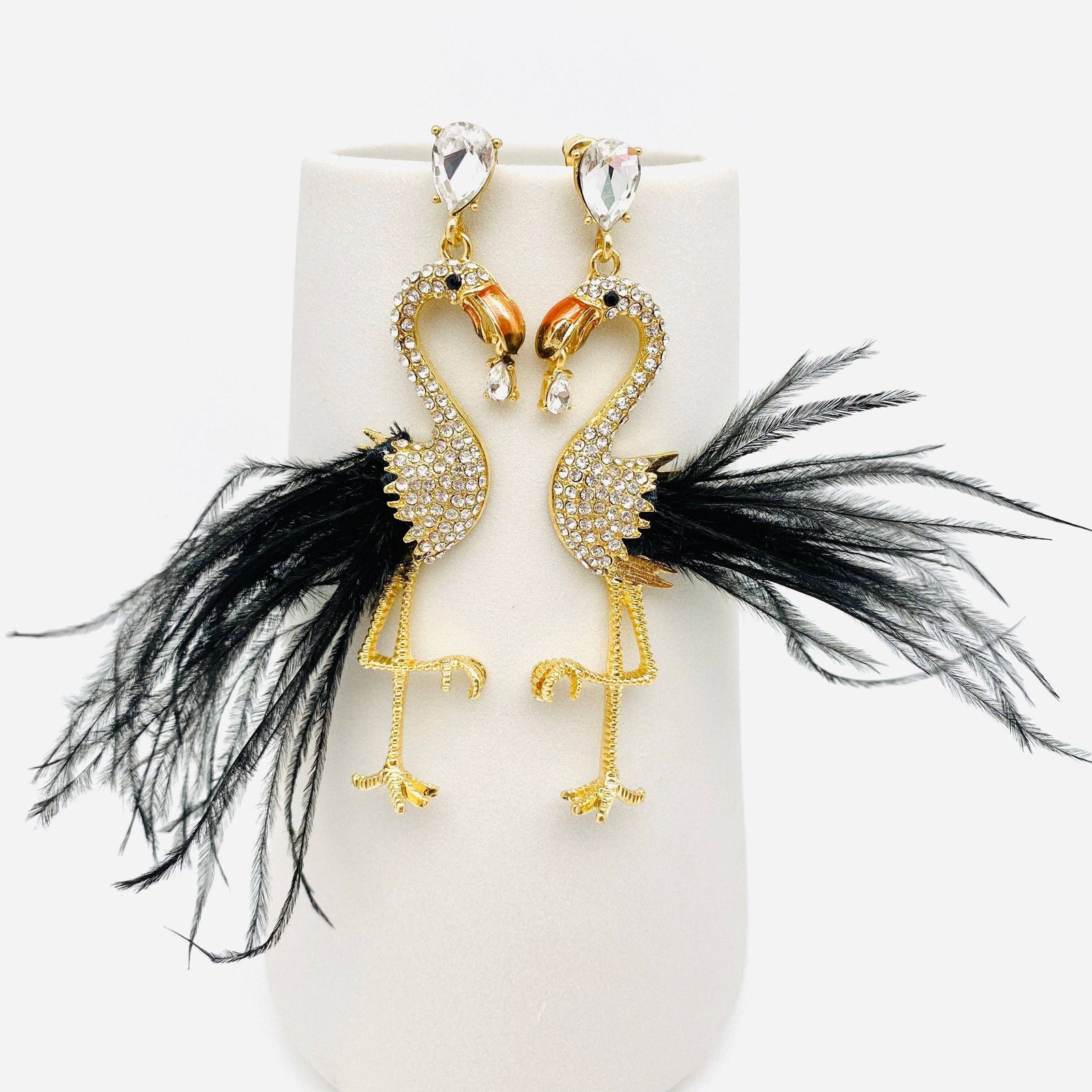 Amanda Bright Designs Feathered flamingo statement earrings on a gold stand against a white background