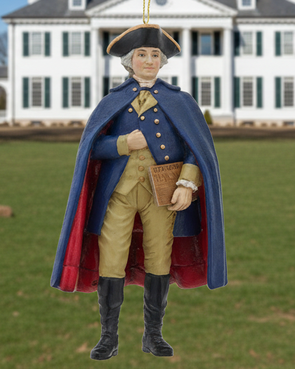 Christmas Cheer All Year 250th USA birthday George Washington Ornament in colonial attire with a blue coat and red interior, holding the U.S. constitution