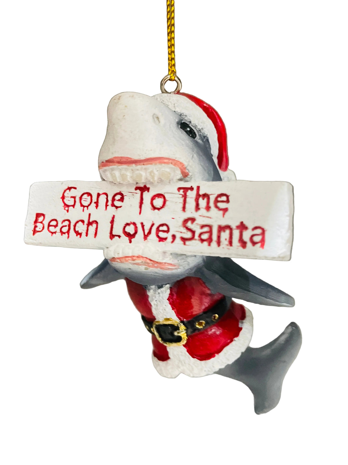 A shark-shaped Christmas ornament wearing a Santa hat and Santa suit, holding a white sign that reads 'Gone To The Beach Love, Santa' in red lettering