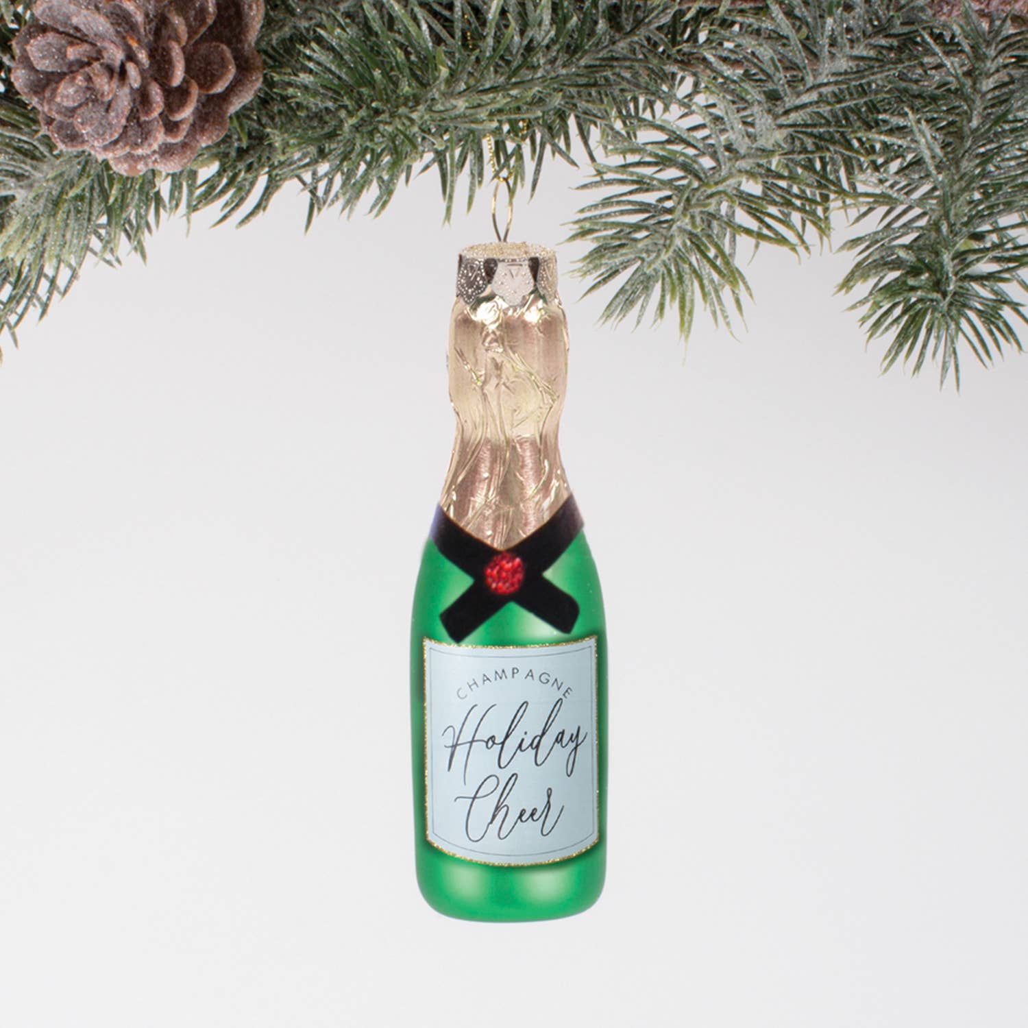 Christmas Cheer All Year Decorative champagne bottle ornament with 'Holiday Cheer' label hanging on a Christmas tree.