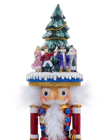 A festive nutcracker figurine with a decorated green Christmas tree and small holiday characters on its hat, set against a plain white background.