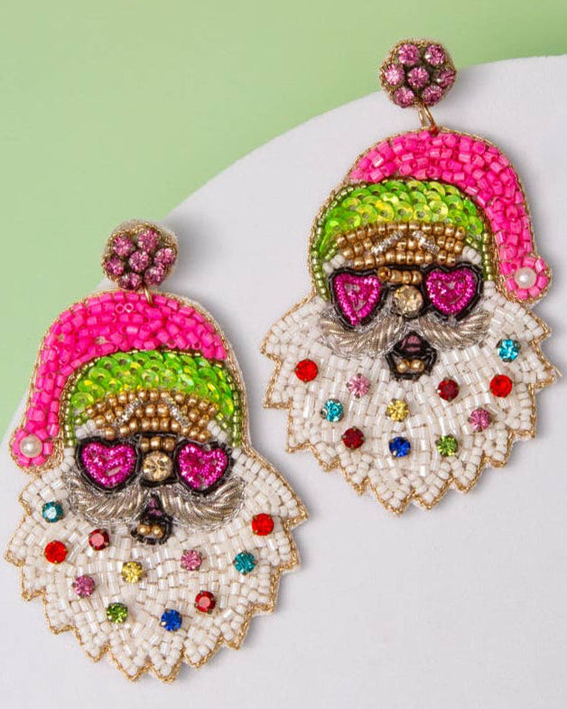 A pair of beaded dangle earrings shaped like Santa's beard and hat, featuring pink, green, white, and gold beadwork with colorful rhinestone accents, shown on a plain white background.