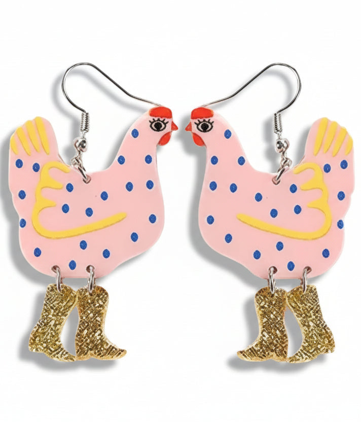 Chicken-shaped earrings with pink bodies, blue polka dots, yellow beaks, and gold cowboy boots on a white background.