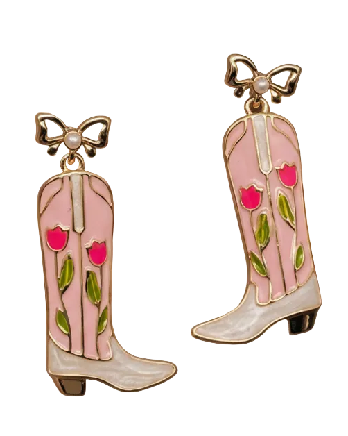 Christmas Cheer All Year dangling cowboy boot earrings with a pink and white faux-pearl finish, decorated with pink flowers and green leaves, and topped with gold bow details with pearl accents.