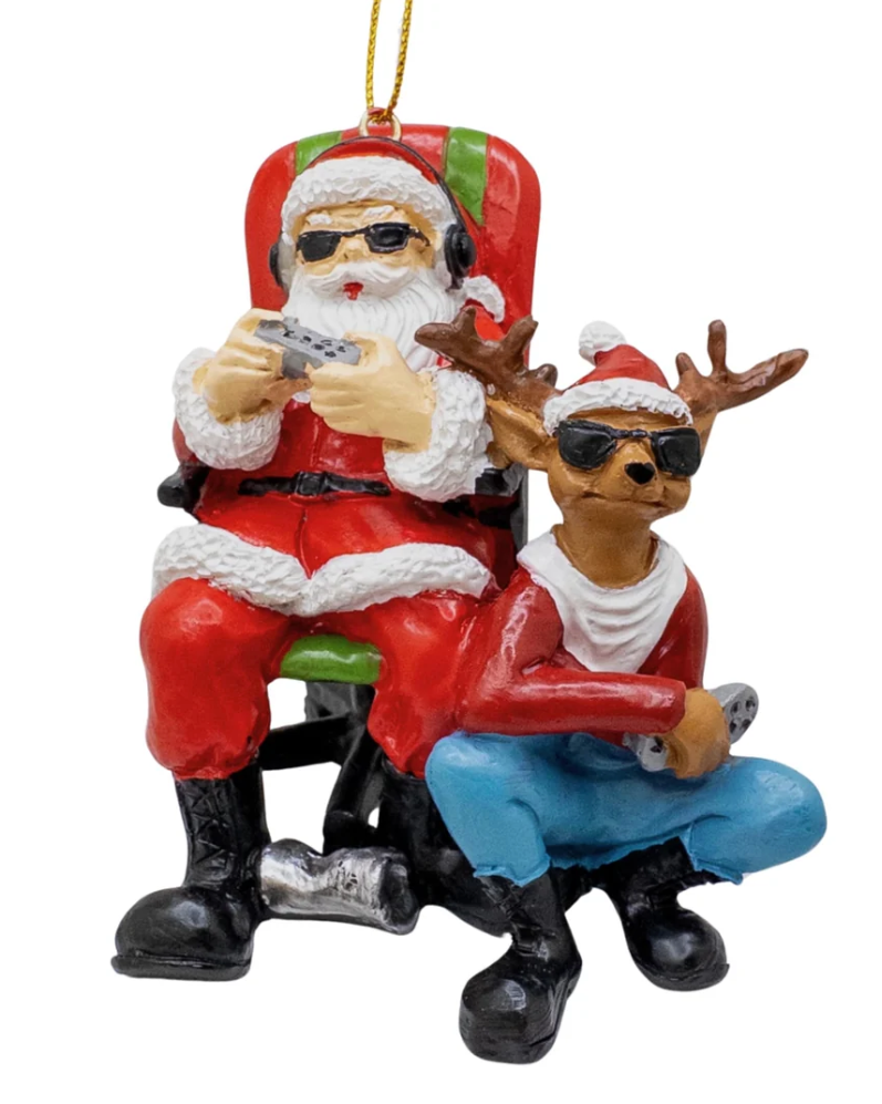 A festive Christmas ornament depicting Santa Claus and a reindeer sitting nearby in a red armchair, both wearing sunglasses and holding video game controllers, with a gold hanging loop at the top.