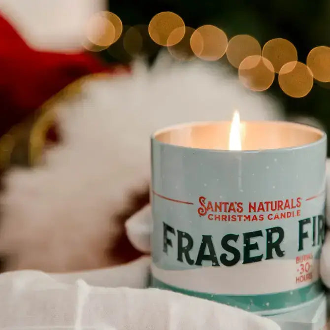 Christmas Cheer All Year Candle in a tin labeled 'Santa's Naturals Fraser Fir' with a festive design.
