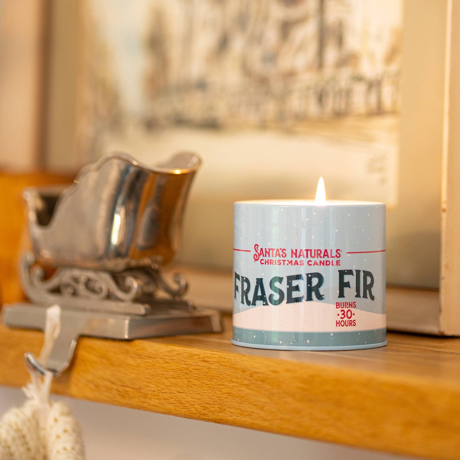 Christmas Cheer All Year Candle labeled 'Fraser Fir' on a wooden shelf with decorative items.