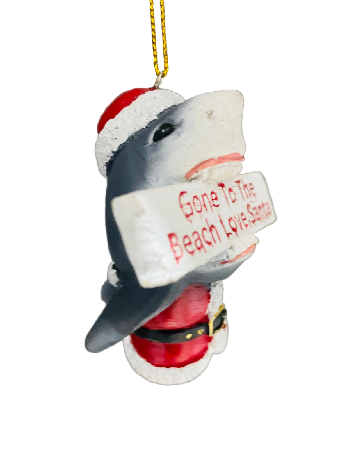 A shark-shaped Christmas ornament dressed in a Santa hat and Santa pants, holding a sign that reads 'Gone To The Beach Love, Santa'.