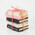 Christmas Cheer All Year Stack of decorative books ornament tied with red and white string on a white background