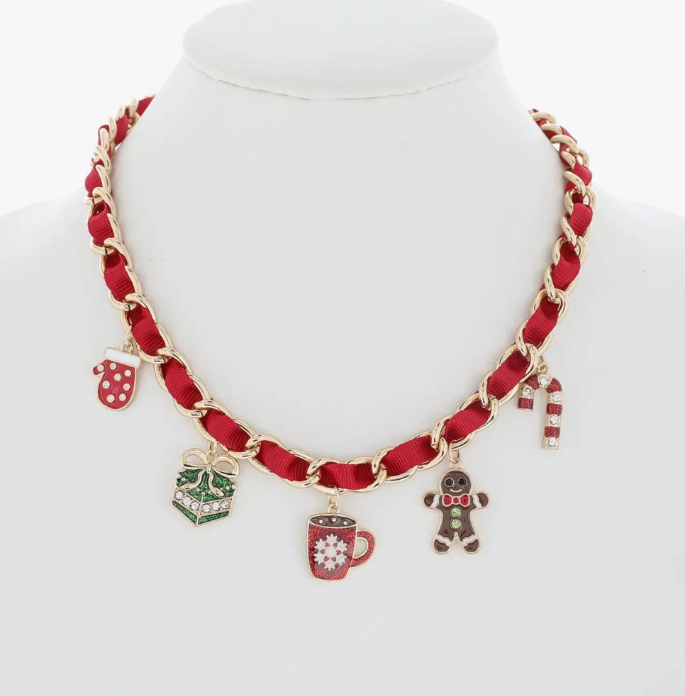 Woman wearing a green dress and red necklace with christmas charms against a neutral background