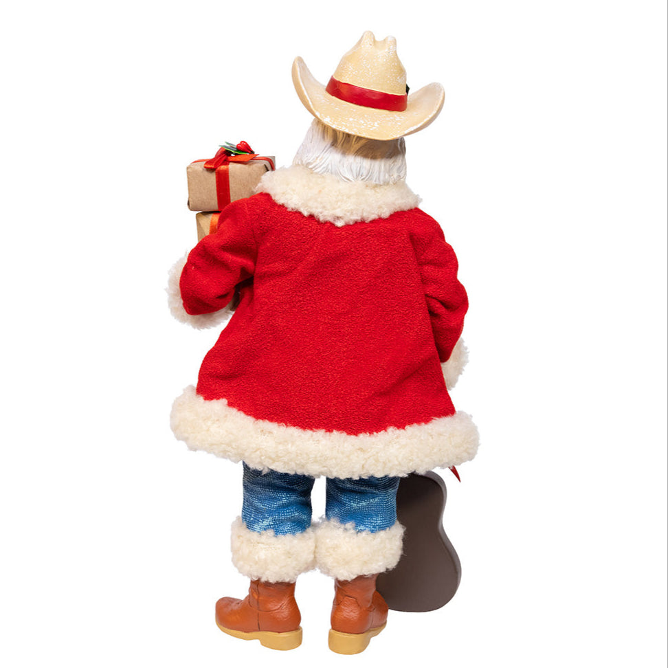 Christmas Cheer All Year Fabriche Cowboy Santa Claus figure holding a guitar and gift boxes on a white background