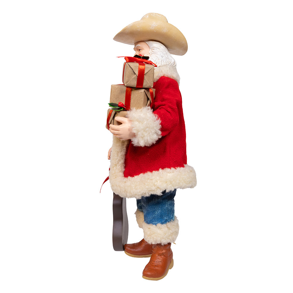 Christmas Cheer All Year Fabriche Cowboy Santa Claus figure holding a guitar and gift boxes on a white background