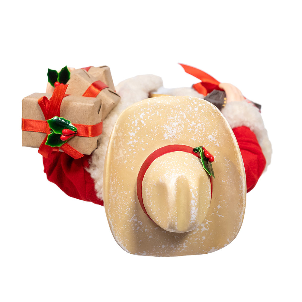 Christmas Cheer All Year Fabriche Cowboy Santa Claus figure holding a guitar and gift boxes on a white background