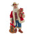 Christmas Cheer All Year Decorative Santa Claus Cowboy figure FA0217 holding a guitar and gift boxes in a festive setting with a fireplace and Christmas tree.