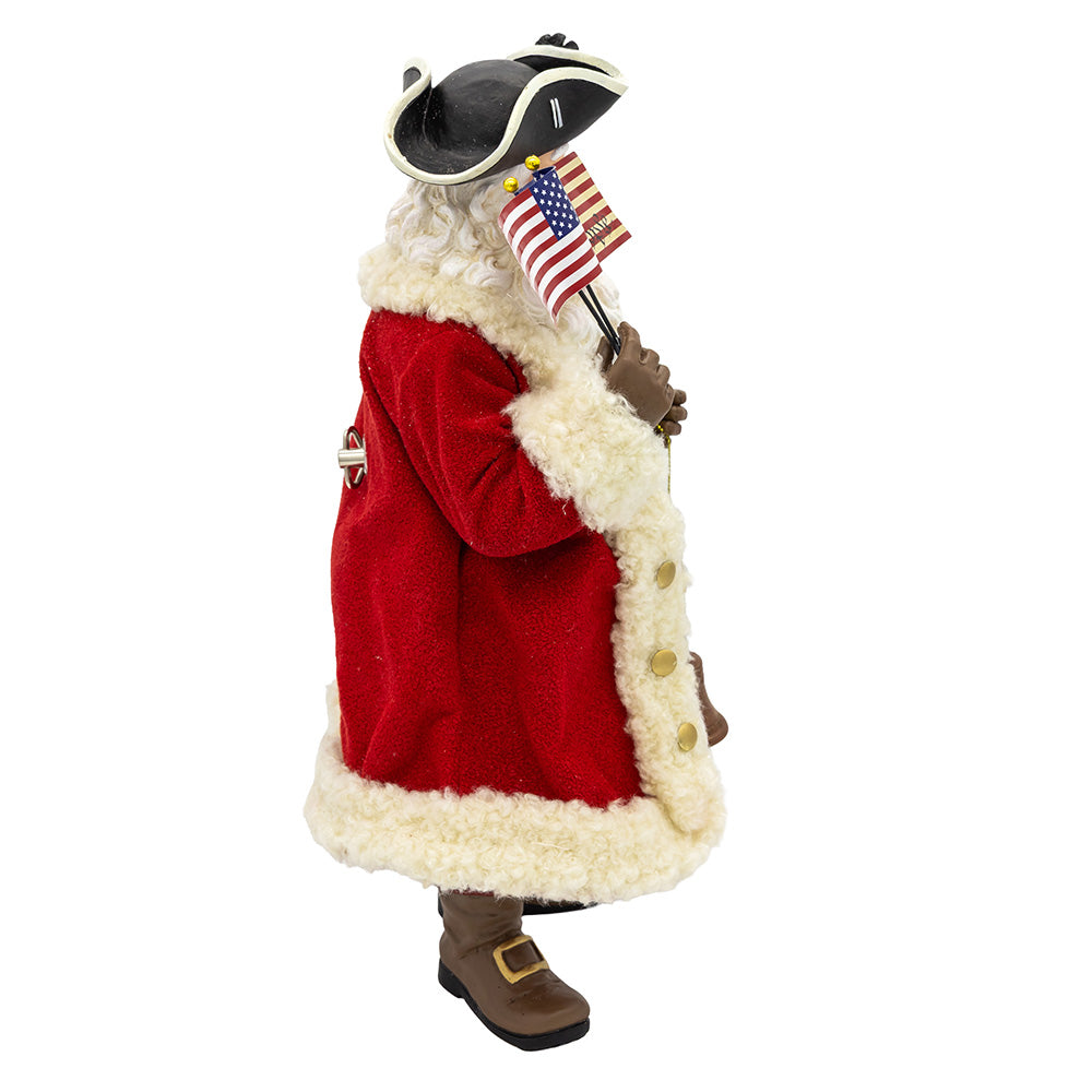 Christmas Cheer All Year FA0231 Santa 250th Figurine of a character in a red coat with white fur trim, holding an American flag on a white background