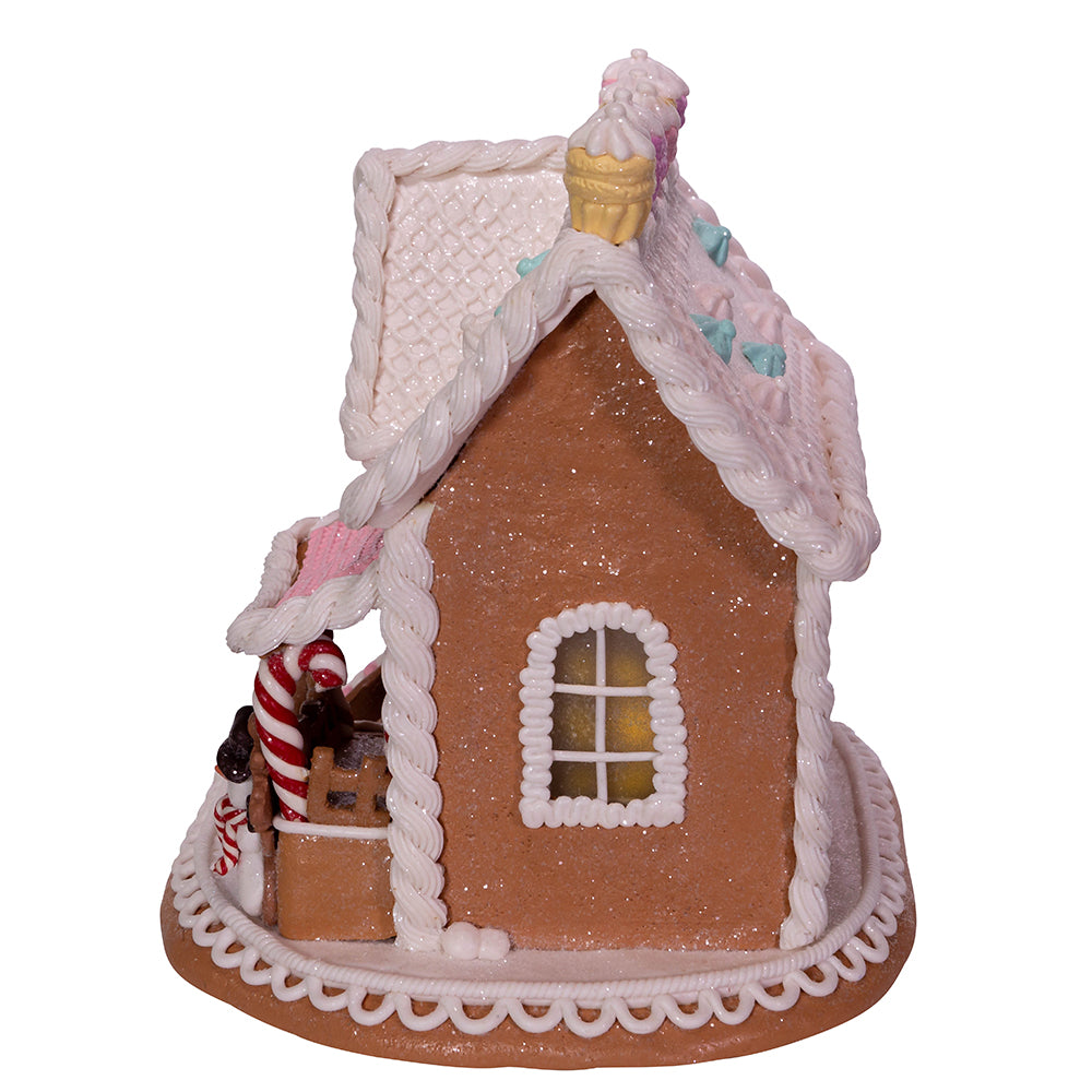 Decorative gingerbread house with a candy cane and ice cream cone on a white background