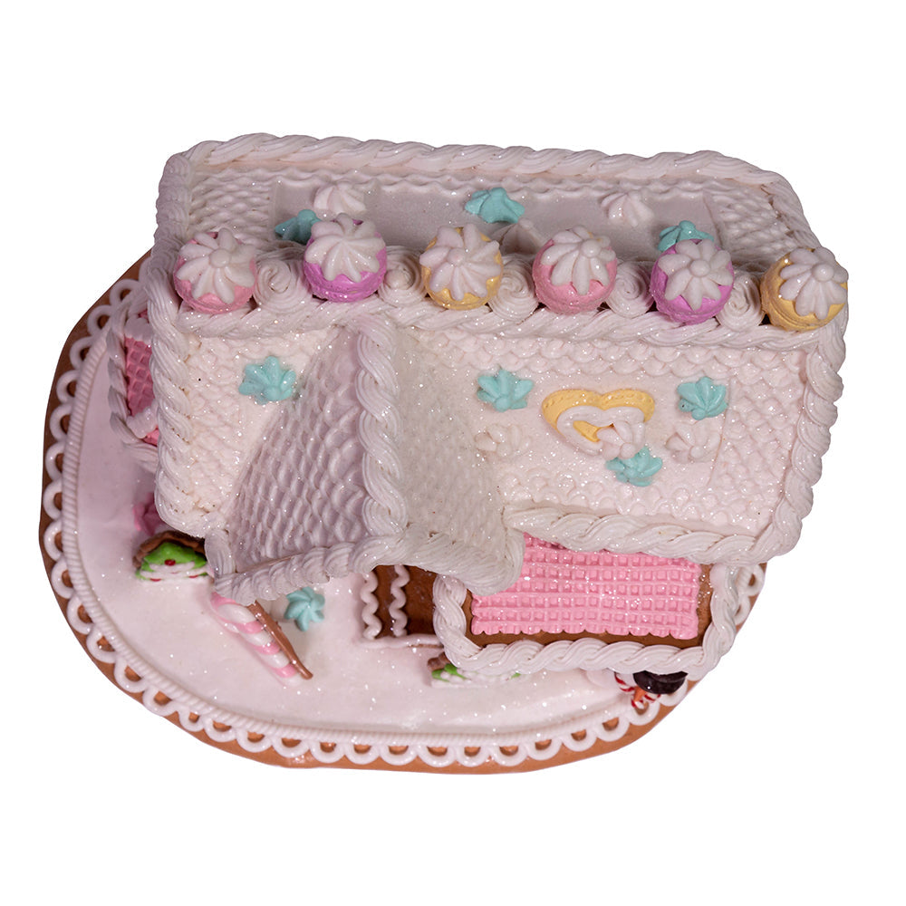 Decorative gingerbread house with pink interior and candy details on a white background