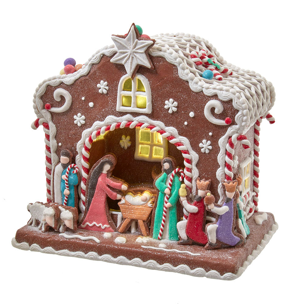 Decorative gingerbread house with nativity scene figures on a white background