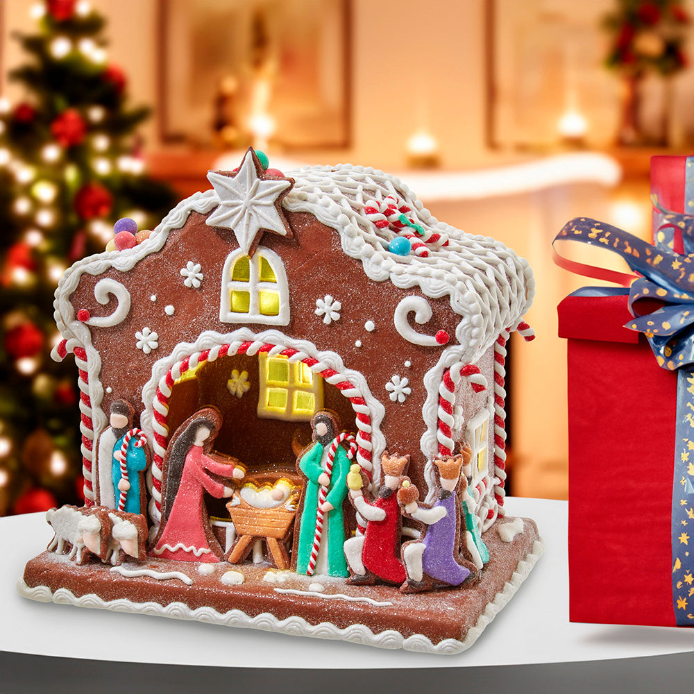Decorative gingerbread house with nativity scene on a table with a blurred festive background