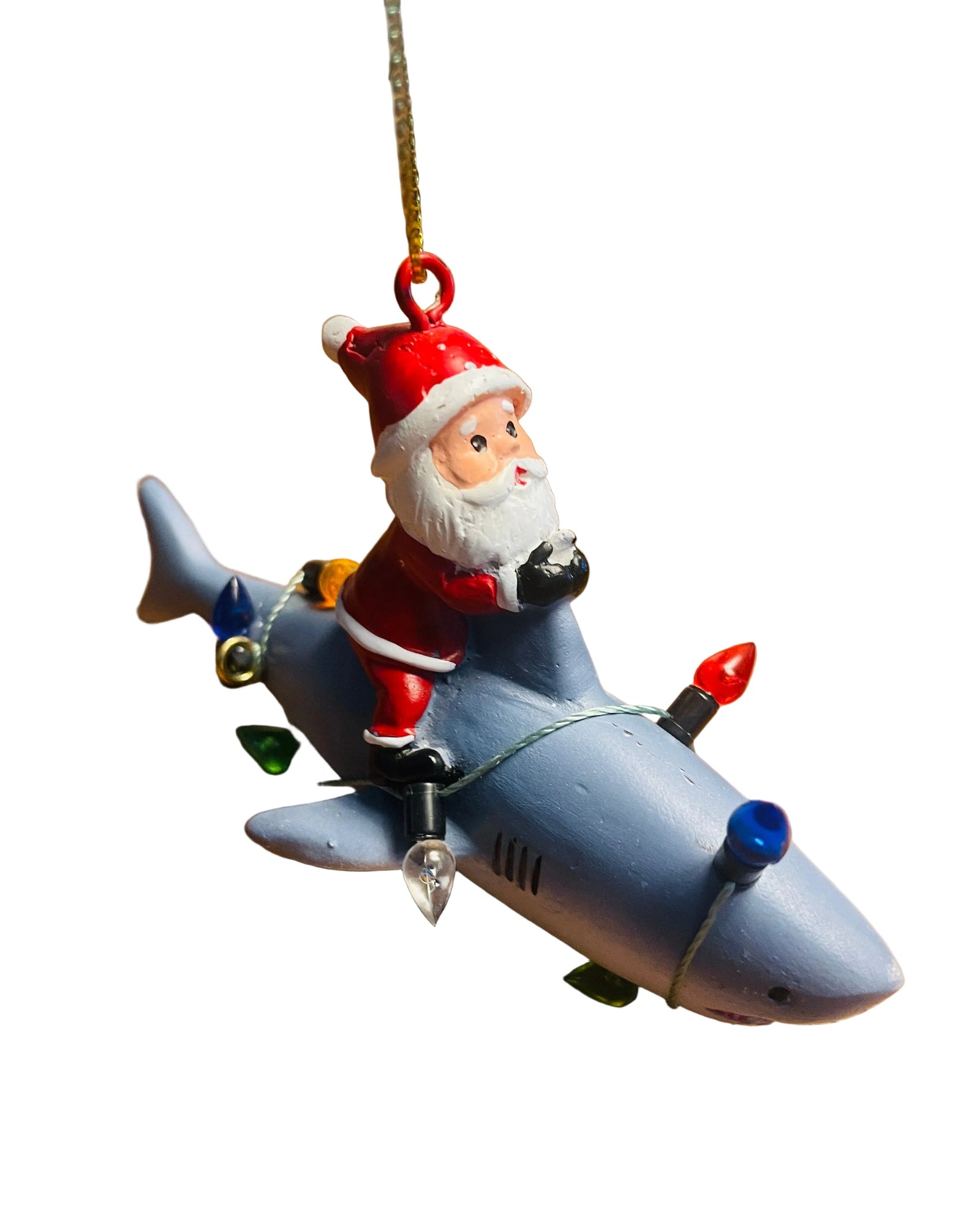 A Santa Claus Christmas ornament riding a gray shark, decorated with colorful Christmas lights